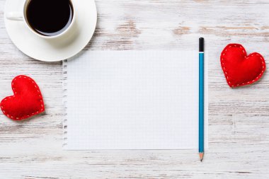Kahve fincanı not defteri kalem ve ahşap yüzeyde iki kırmızı kalp
