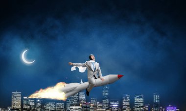 Arka plan üzerinde gece cityscape ve mavi gökyüzü ile roket üzerinde uçan takım elbiseli genç işadamı kavramsal görüntü.