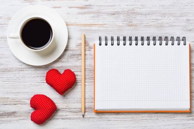 Kahve fincanı not defteri kalem ve ahşap yüzeyde iki kırmızı kalp