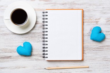 Kahve fincanı not defteri kalem ve ahşap yüzeyde iki kalp