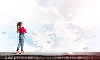 Sevimli kız etrafında uçan çatı ve kağıt uçaklar binasında ayakta