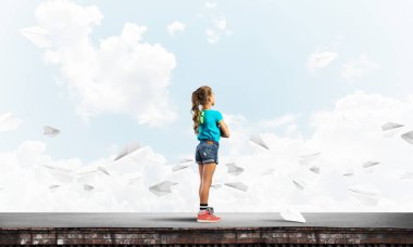 Sevimli kız etrafında uçan çatı ve kağıt uçaklar binasında ayakta