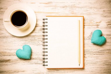 Kahve fincanı not defteri kalem ve ahşap yüzeyde iki kalp