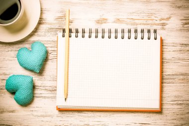 Kahve fincanı not defteri kalem ve ahşap yüzeyde iki kalp