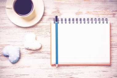 Kahve fincanı not defteri kalem ve ahşap yüzeyde iki kalp