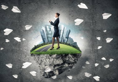 Yeşil yüzen adada beton zemine karşı duran kendine güvenen zarif bir iş kadını.