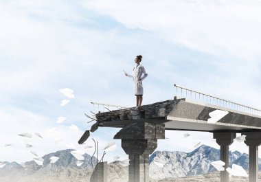 Arka planda peyzaj görünümü ile kırık köprünün kenarında uçan kağıt uçakları arasında duran beyaz üniforma ayakta güvenilir tıbbi sanayi çalışanı. Tıbbi küre konsepti