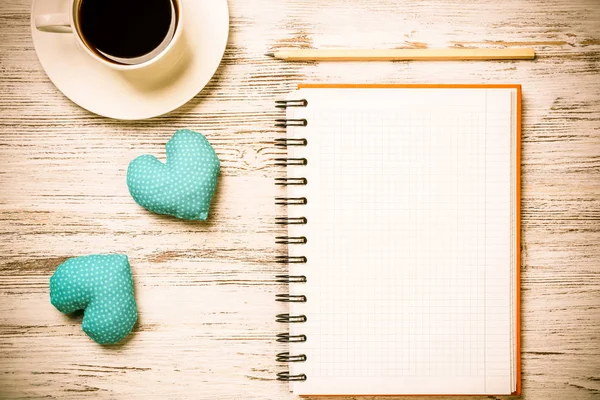 Kahve fincanı not defteri kalem ve ahşap yüzeyde iki kalp
