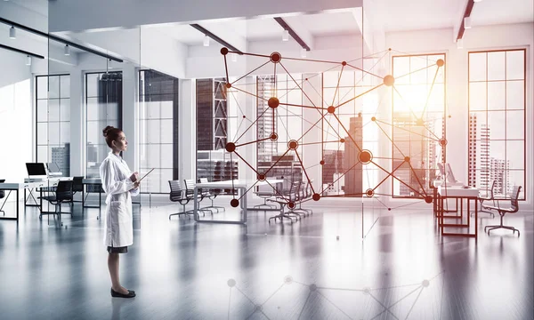 Confident medical industry employee standing inside white hospital building and examining black network structure. Modern technologies for medical industry