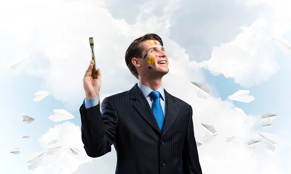 野心的で若いビジネスマンの肖像画を手に描いたまま 青い曇りの Skyscape に向かって立っているときに 背景の上に紙飛行機で飛んだ — ストック写真