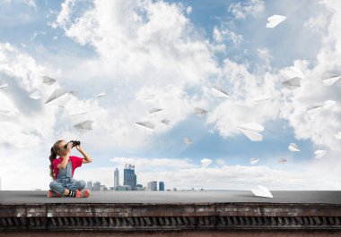 Dürbünle bakan, okul çağındaki sevimli kız çatıyı inşa ediyor.