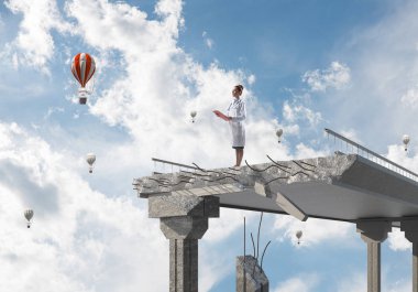 El ve peyzaj görünümü ve arka planda uçan hava balonları tablet ile kırık köprünün kenarında duran genç kadın doktor. Medikal Sanayi konsepti