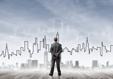 İşadamı arkasını dönüp modern iş merkezinin siluetine bakıyor.