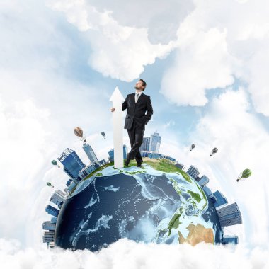 Takım elbiseli, kendinden emin ve başarılı bir iş adamı elinde kocaman beyaz bir okla arka planda bulutlu bir gökyüzü olan Dünya 'yı işaret ediyor. Bu görüntünün elementleri Nasa tarafından döşenmiştir