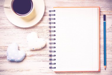 Kahve fincanı not defteri kalem ve ahşap yüzeyde iki kalp