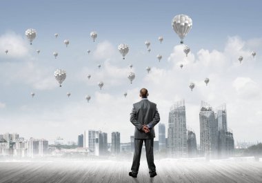 Arka ayakta ve havada uçan aerostats bakarak bir işadamı