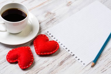 Kahve fincanı not defteri kalem ve ahşap yüzeyde iki kırmızı kalp