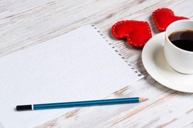 Kahve fincanı not defteri kalem ve ahşap yüzeyde iki kırmızı kalp
