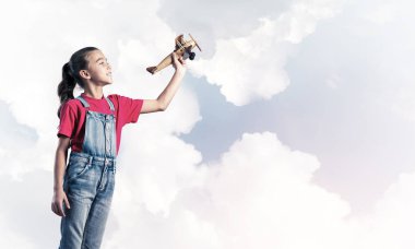 Elinde retro uçak modeliyle tulumlu şirin bir kız çocuğu.