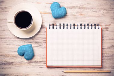 Kahve fincanı not defteri kalem ve ahşap yüzeyde iki kalp