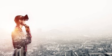 Sanal gerçeklik kulaklığı olan genç bir adam ya da şehrin arka planında 3 boyutlu gözlüklü.