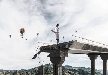 El ve peyzaj görünümü ve arka planda uçan hava balonları tablet ile kırık köprünün kenarında duran genç kadın doktor. Medikal Sanayi konsepti