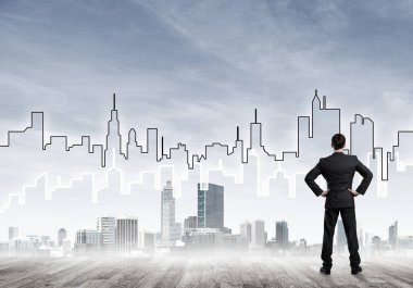 İşadamı arkasını dönüp modern iş merkezinin siluetine bakıyor.