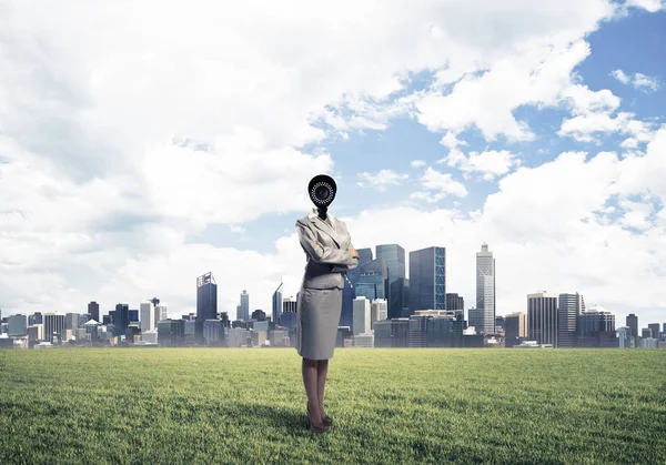 Macchina fotografica diretto donna in piedi su erba verde contro le città moderne — Foto Stock