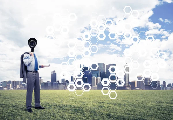 Camera headed man standing on green grass against modern citysca — Stock Photo, Image