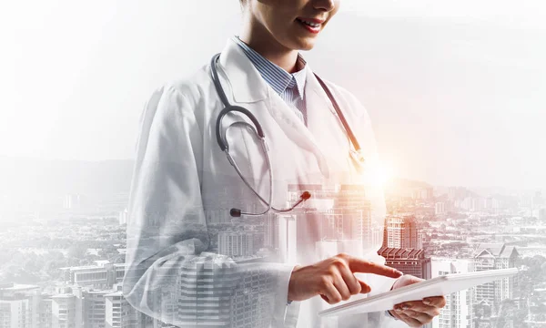 タブレットを使用して 白いスーツで医療従事者の画像をクローズアップし 背景に都市のビューで屋外に立って 医療業界の概念 二重露光 — ストック写真