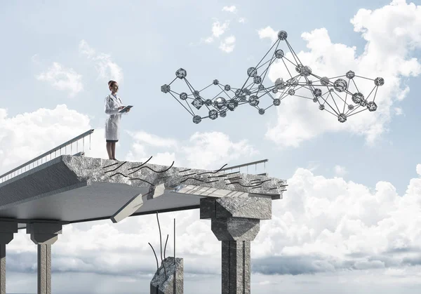 Genç ve profesyonel kadın doktor beyaz tıbbi elbise ağ yapısı okuyan kırık köprü ayakta iken. Tıbbi endüstri konsepti. Doktor kullanarak tablet