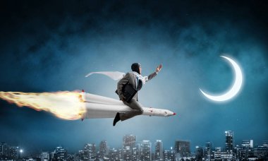 Arka plan üzerinde moon ile gece cityscape ve mavi karanlık gökyüzü ile roket üzerinde uçan takım elbiseli genç işadamı kavramsal görüntü.