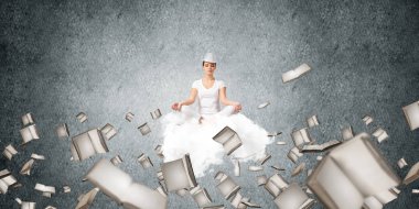 Kadın beyaz giyim gözler tutmak kapalı ve seyir üzerinde uçan bulut kitaplar ile gri karanlık duvar arka plan üzerinde uçan arasında meditasyon sırasında konsantre.