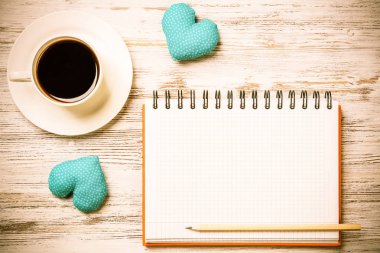 Kahve fincanı not defteri kalem ve ahşap yüzeyde iki kalp