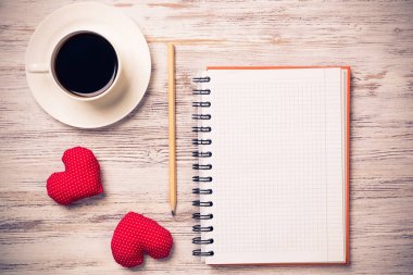 Kahve fincanı not defteri kalem ve ahşap yüzeyde iki kırmızı kalp