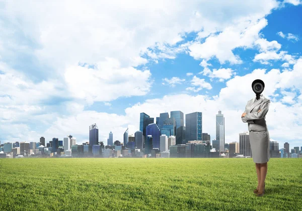 현대 도시 풍경을 배경으로 푸른 잔디 위에서 있는 사진기 여자 — 스톡 사진
