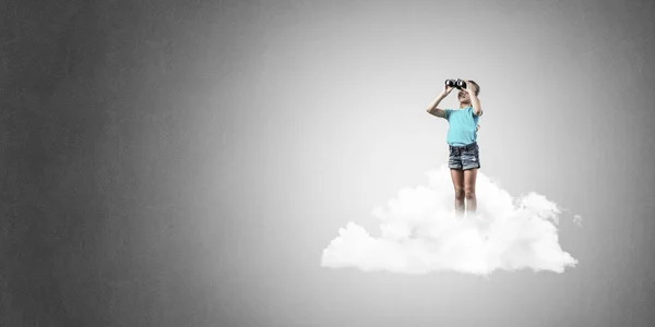 雲の上に立って 双眼鏡で探してかわいい子供女の子 — ストック写真