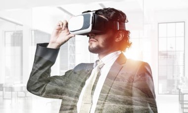 Genç yakışıklı işadamı modern iç arka plan karşı sanal kask içinde. Karışık teknik
