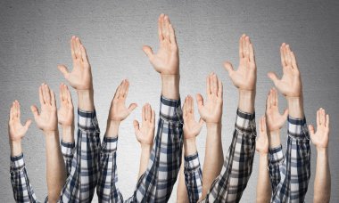 Oy verme jestini gösteren bir sıra adam eli. Katılım ve anlaşma işaretleri grubu. İnsan elleri gri duvarın arka planında siler. Birçok kol birlikte kaldırdı ve mevcut popüler jest.