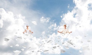 Genç çift gözleri koruma kapalı ve seyir kağıt uçaklar hava bulutlu gökyüzü ile arka plan üzerinde uçan arasında meditasyon sırasında konsantre.