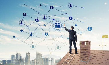 Delikanlı çatıda dikiliyor ve bağlantı hatları çiziyor. Karışık ortam