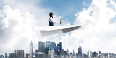 Megapolis'in üstünde kağıt uçak kullanan havacı. Kağıt düzlemde oturan ve direksiyon u tutan pilotun yan görünümü. Yüksek gökdelenler ve ofis binaları ile Cityscape. Karma medya iş kavramı