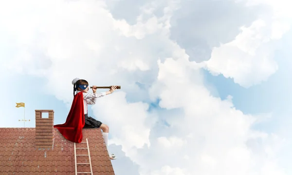 Małe Dziecko Maskę Pelerynę Siedzi Dachu Cegły Patrząc Luneta Techniki — Zdjęcie stockowe