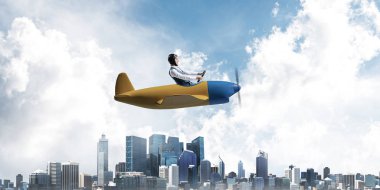 Küçük uçak kabininde oturan pilot ile iş liderliği ve motivasyon konsepti. Havacı şapkalı komik adam ve şehrin üzerinde pervane uçağı süren gözlükler. Yüksek binalarile modern megapolis