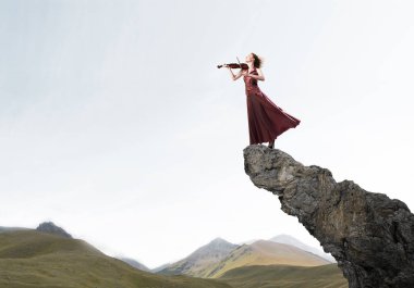 Keman ayakta rock üst kısmında oynayan genç çekici kız