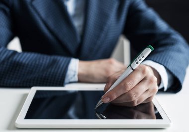 İş elbisesi giyen adam tabletle masada oturuyor