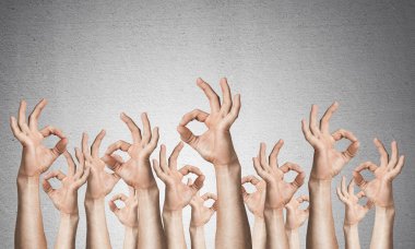 İyi bir jest gösteren bir sıra adam eli. Anlaşma ve onay işareti grubu. İnsan elleri gri duvarın arka planında siler. Birçok kol birlikte kaldırdı ve mevcut popüler jest.