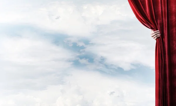 Kırmızı perde ve el tutan arkasında bulutlu manzara — Stok fotoğraf