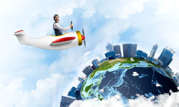 ゴーグルプロペラ機を運転して航空機の帽子の男 高い近代的な建物と地球の地球 小さな飛行機で楽しんでいる面白い男 熱気球と紙飛行機を飛んで青空 — ストック写真