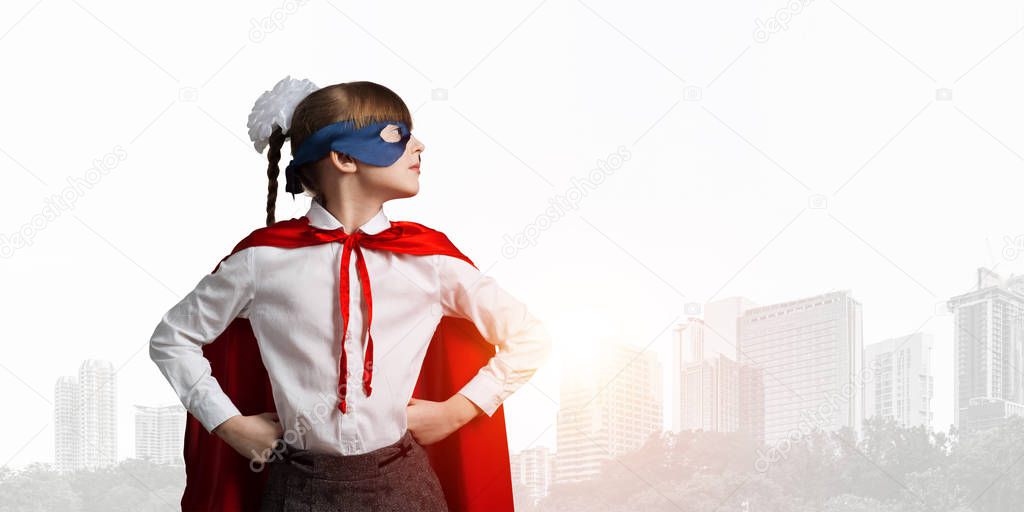 Little confident child in mask and cape plays cool superhero